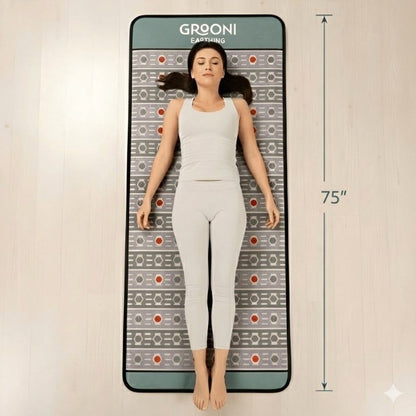 Woman lying on a Grooni PEMF mat with dimensions indicated.