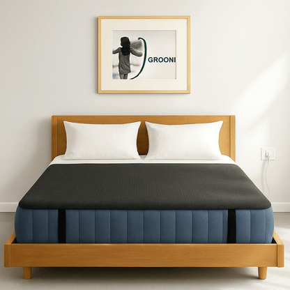 Bed with wooden frame and blue mattress with a grounding mat on topin a room with a framed picture on the wall.