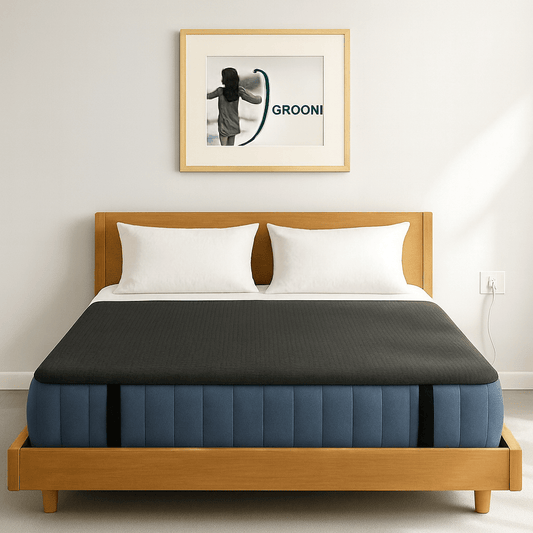 Bed with wooden frame and blue mattress with a grounding mat on topin a room with a framed picture on the wall.
